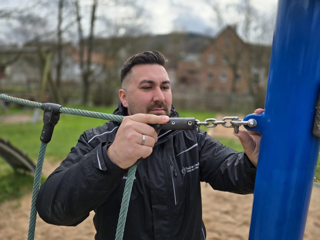 Mann repariert Spielplatzgerät