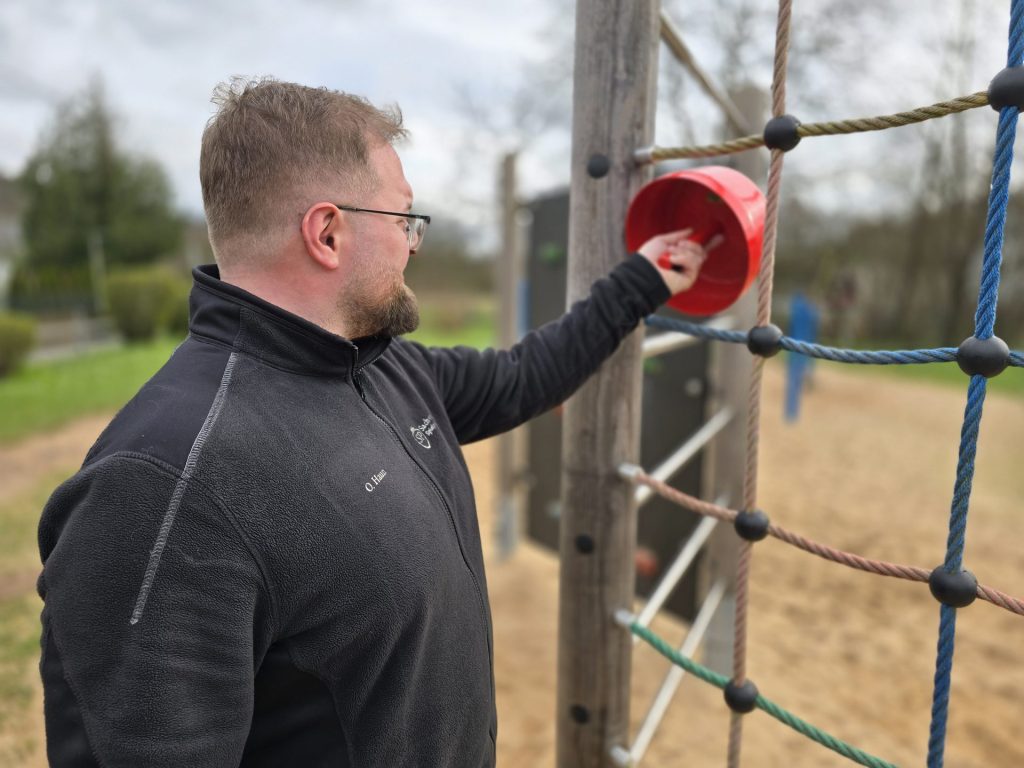 Mann am Spielplatz mit Behälter